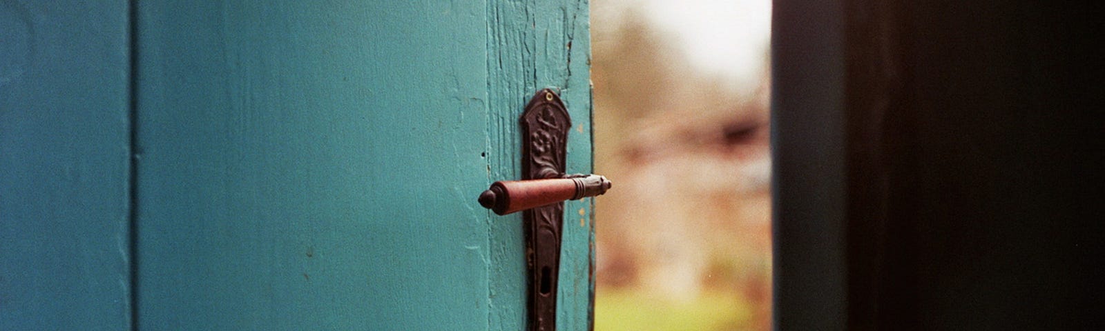 Blue door partially opening to outdoors.