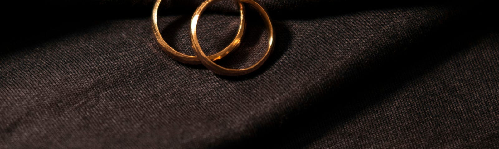 two gold wedding bands on a black cloth