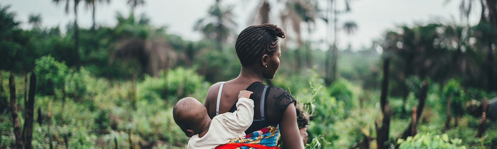 colorful image of a mother who is carrying her baby, strapped on her back.