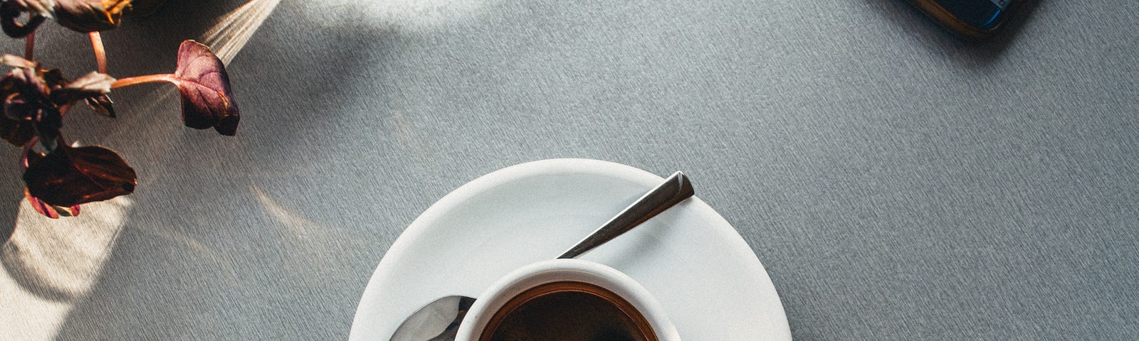 A “bird’s eye” view of a cup of coffee sitting on a table beside a cell phone.