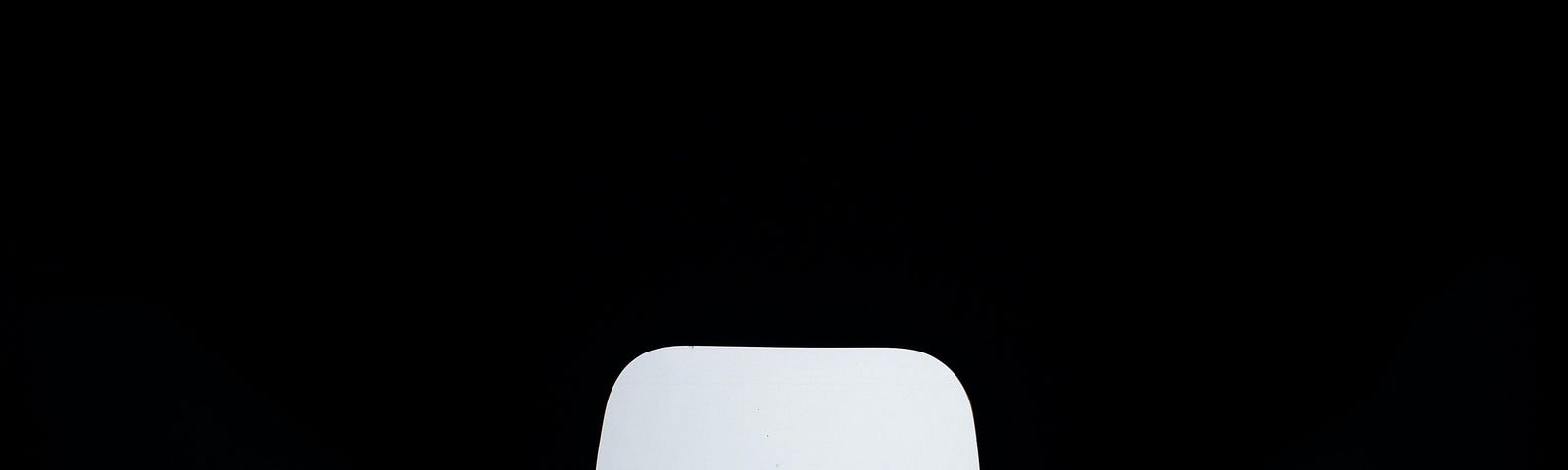 Dark background with a lone white chair