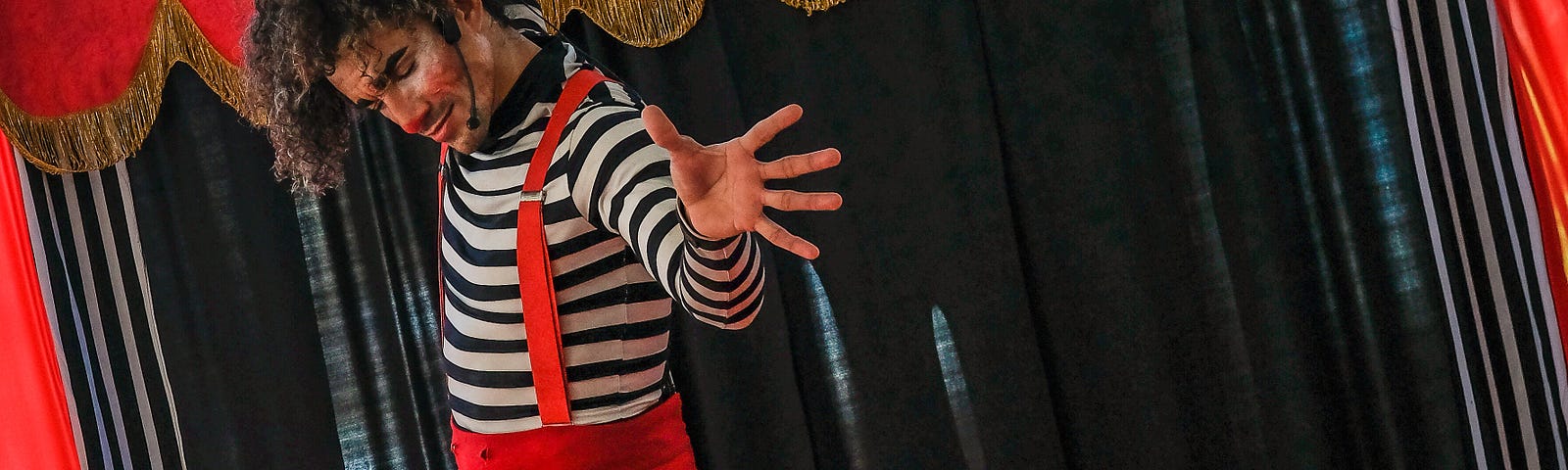clown in red pants on a stage with red curtains