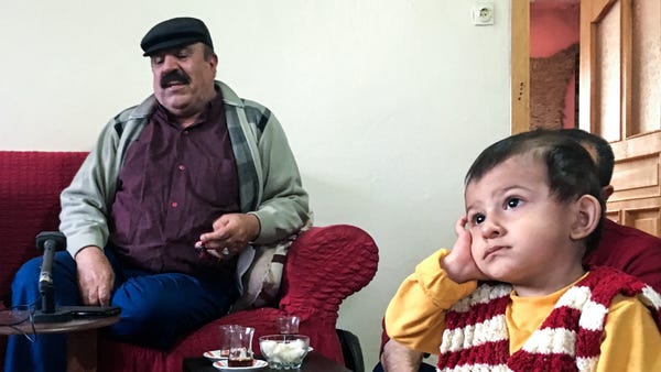 As Mistefa Bedevi sings, 1-year-old Mirhat mimics performance poses, holding his hand over his ear.