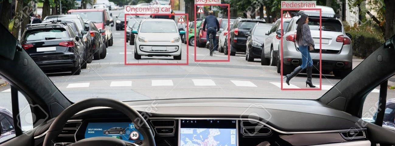 A moving autonomously driven car analyses the road ahead, spotting a car, a pedestrian crossing the road, and a bike rider. The screen displays the path ahead for passengers inside.