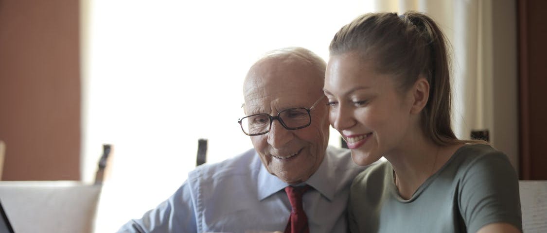 A young woman showing an elderly gentleman how to use a smartphone
