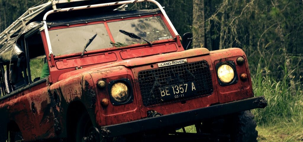 Old Land Rover ripping through mud in a forest. Photo courtesy of ahmed syahrir at Pexels.