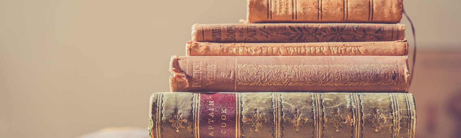 A pile of old dusty books stacked one on top of the other