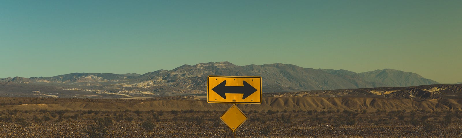 Yellow sign with two-way arrow in the desert