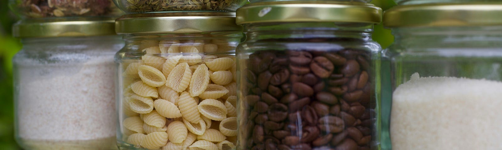 Stacks of clear glass jars with various types of food inside.