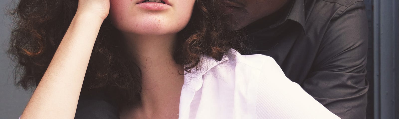Woman in a white shirt, embraced by her partner