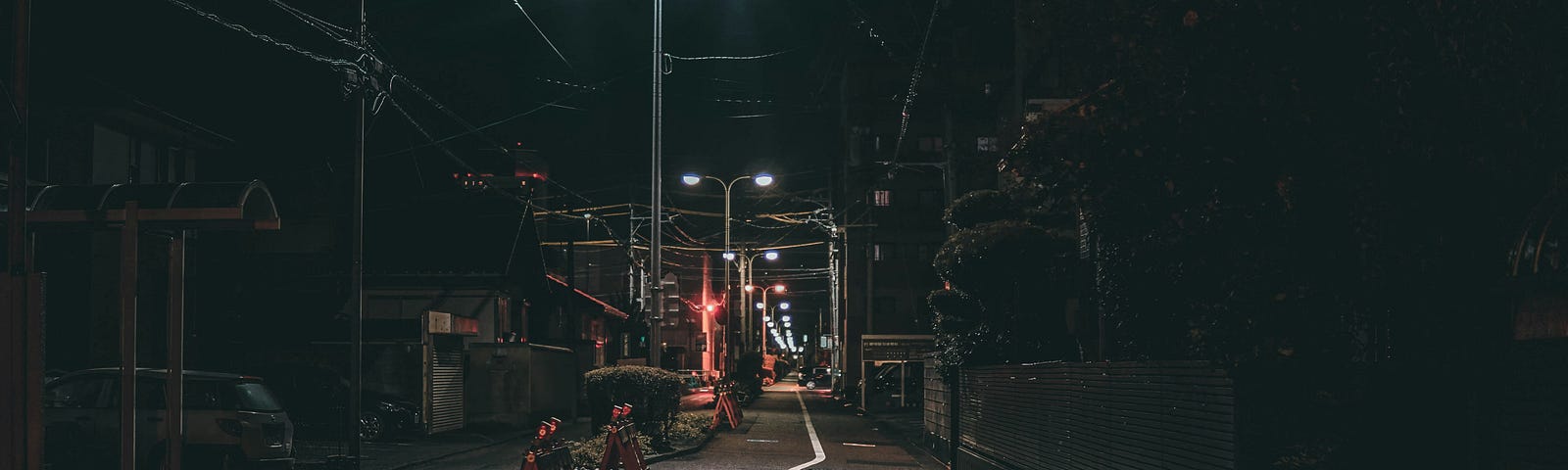 A quiet alley with faded streetlamps and red traffic lamp in front at midnight