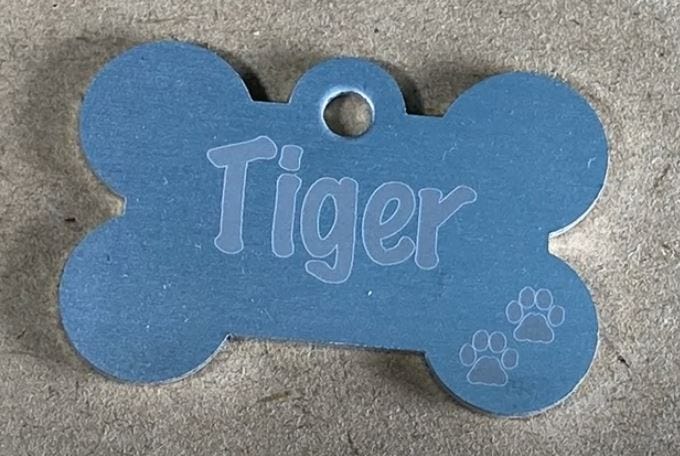 A dog tag with the name “Tiger” engraved on it using a CO2 laser