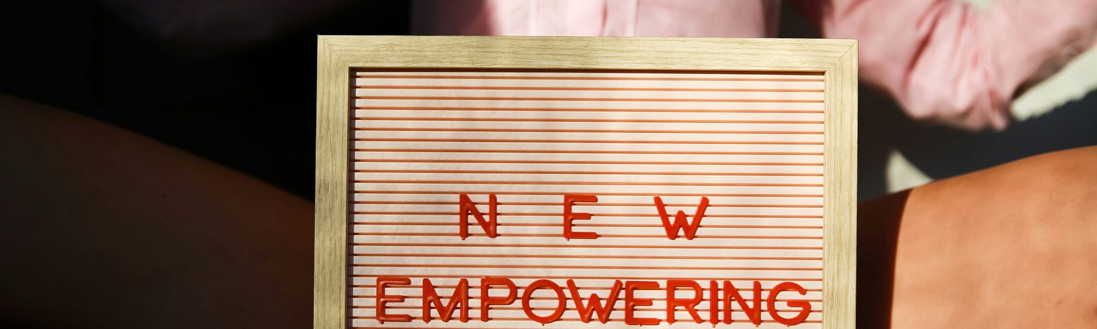 woman holding a wooden sign that says new empowering stories.