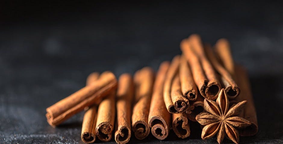 Stack of cinnamon with a star anise on a black surface.