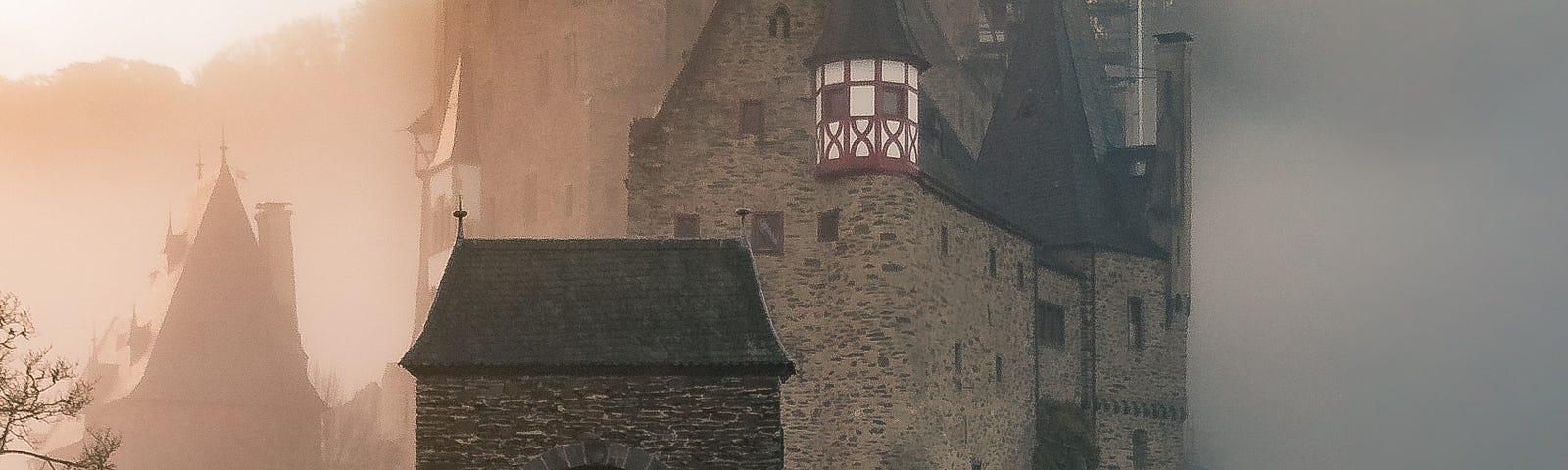 A medieval style castle facing a bridge, with a reflection of the same image in water