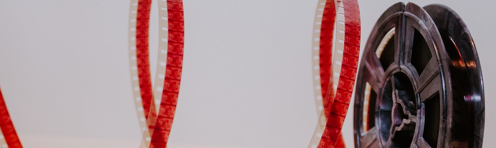 a reel of film with a spiral of red film coming off the reel to the left of the screen