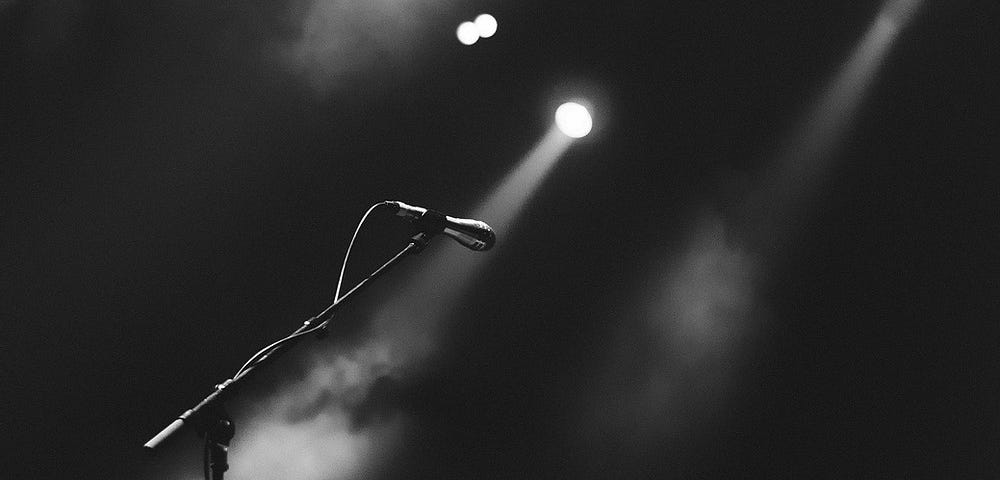 A black and white image of a microphone in a spotlight.