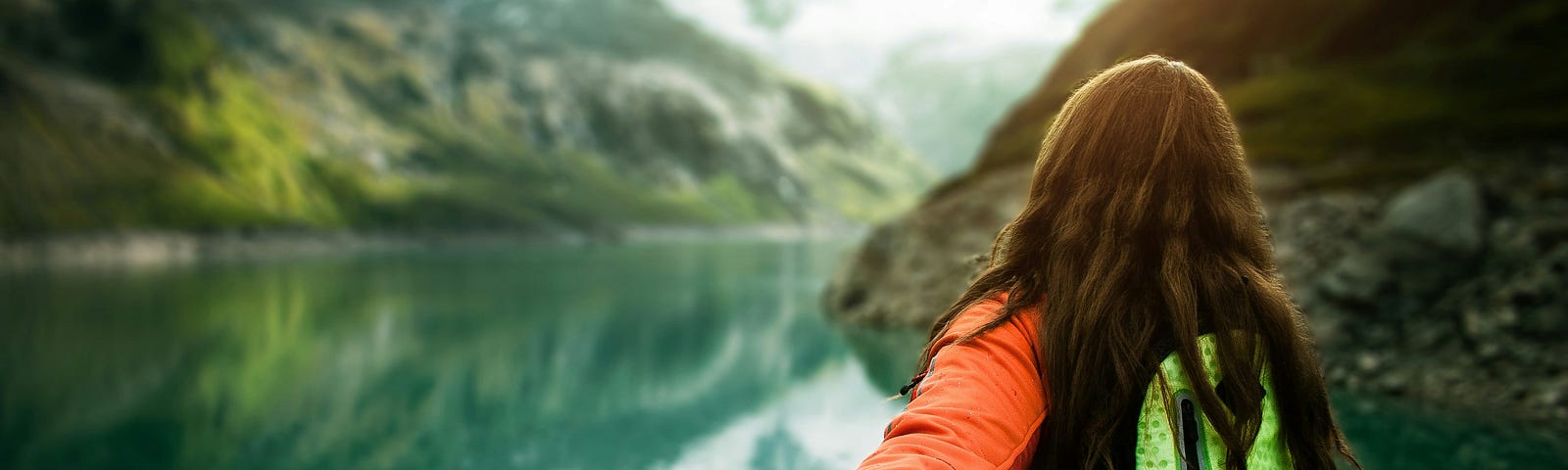 A person holding hands with someone while walking towards a serene mountain lake, symbolizing connection and adventure in nature.