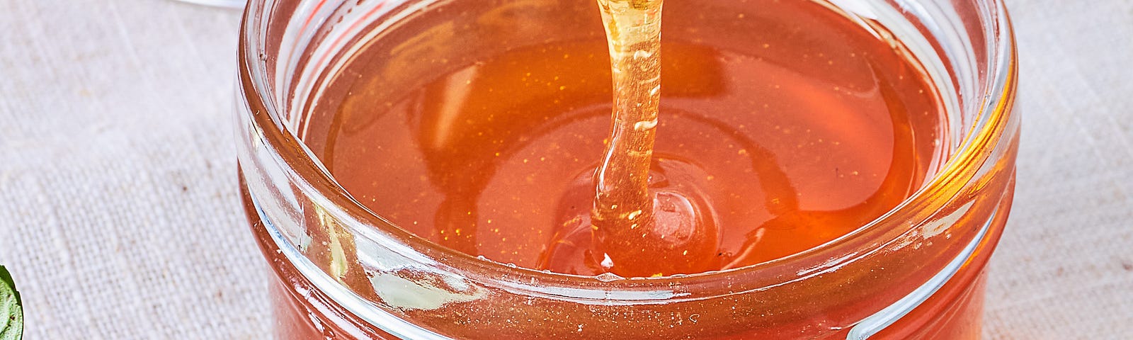 Honey dripping into a jar