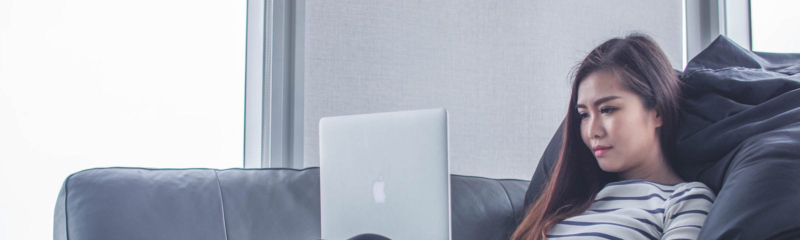 Woman lounging on a couch using a laptop.