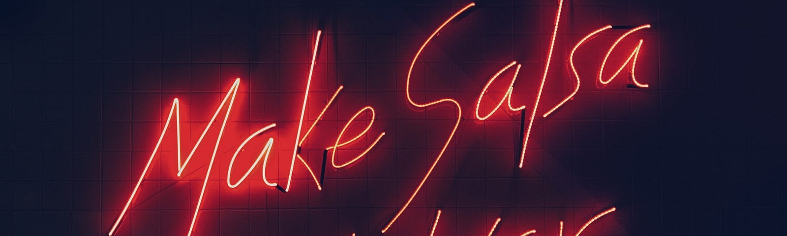 Neon sign that says “make salsa not war” in red on a black background