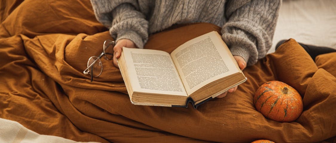 A woman reading a book on a bed