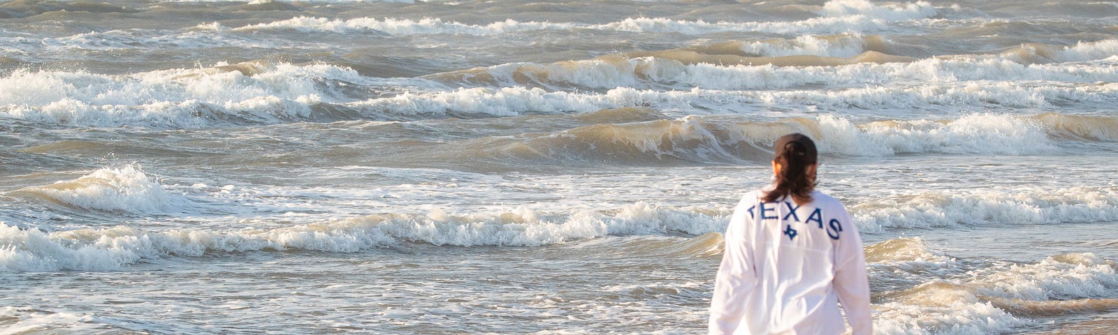 Walker on beach, watching waves on sea