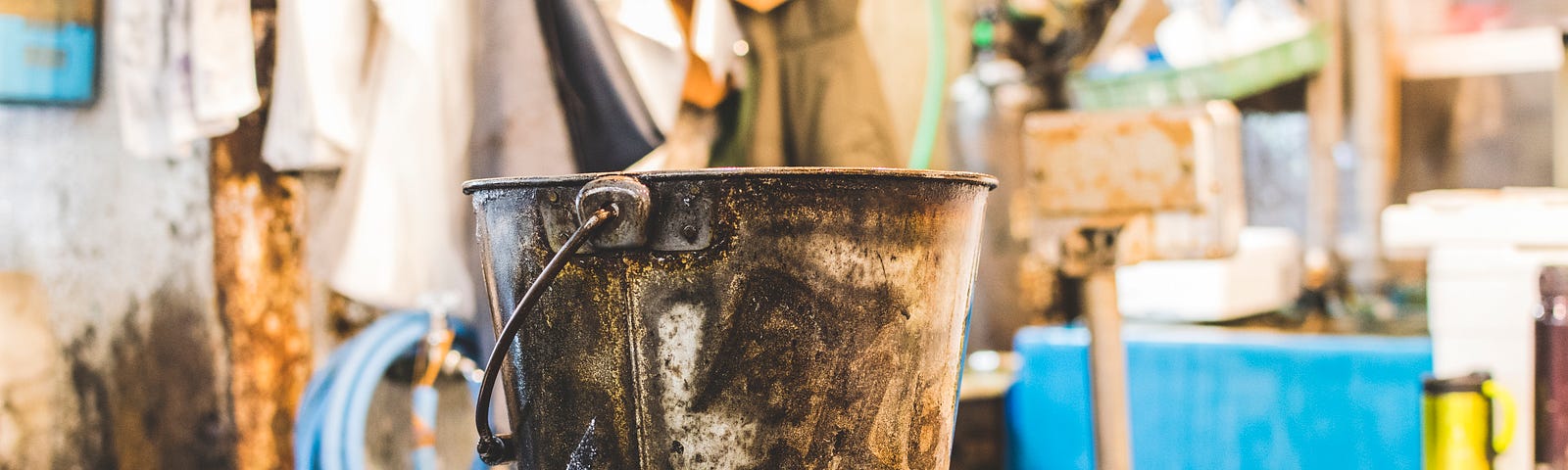 An old dirty bucket sitting on workshop table