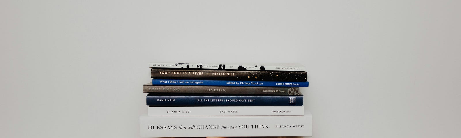 hand lifting books against a white wall background