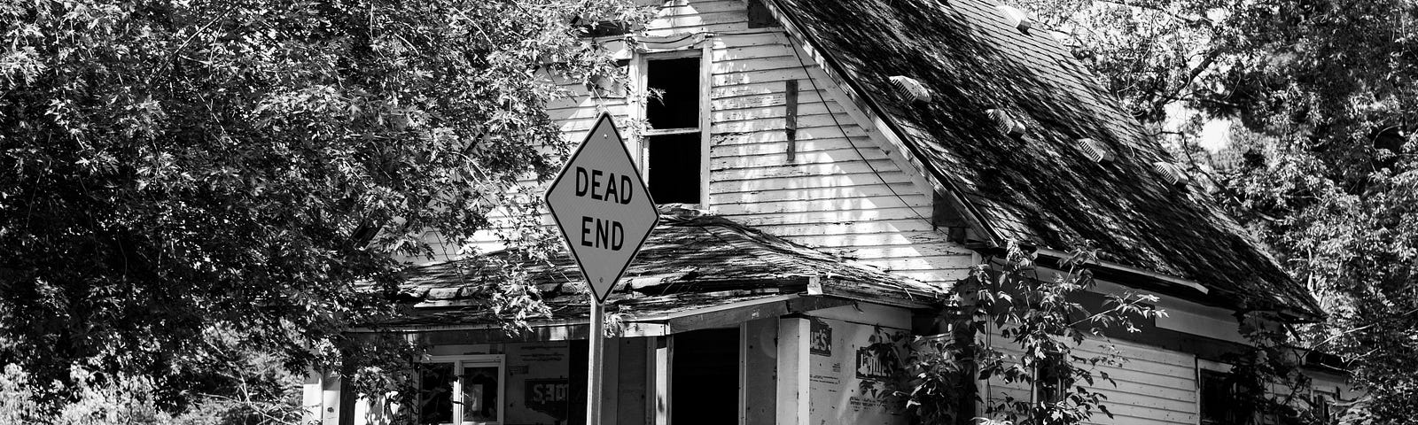 Black and white photo of shack in front of Dead End sign