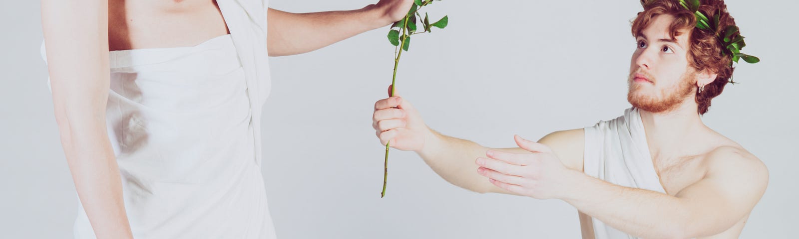 One person is kneeling and attempting to give a rose to a person standing looking disinterested and pushing the flower away.