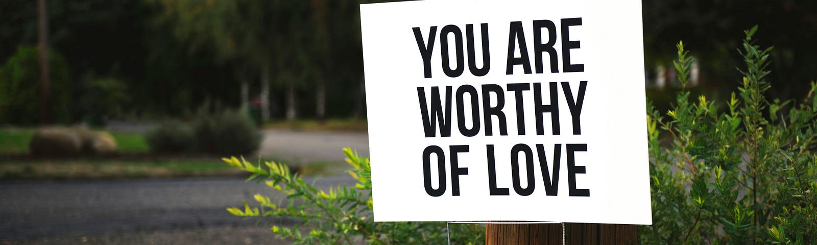 A simple sign put up on someone’s lawn. It says: You Are Worthy Of Love