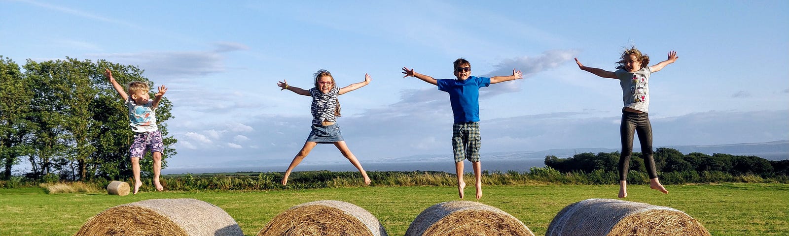 Children having fun jumping on haystack