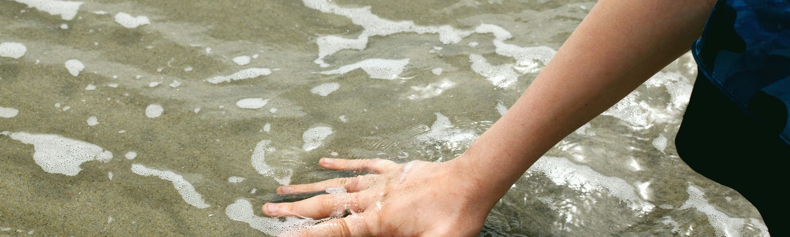 A hand immersed in shallow water