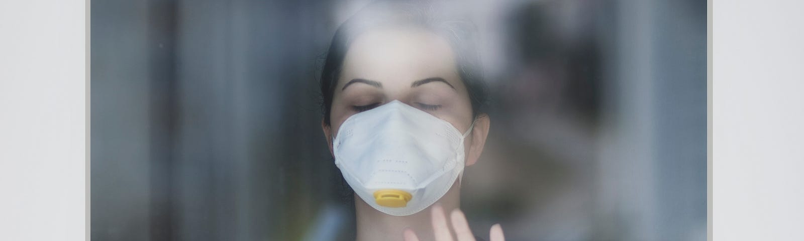 Photo of woman with face mask behind glass wall. Photo posted on Dr. James Goydos 2021 article about mask requirements and debate between Dr. Fauci and Rep. Jordan