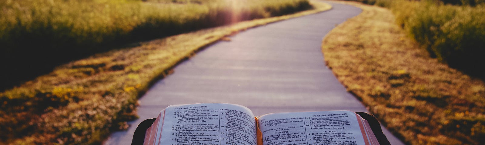 Man holding a Bible while standing still on a sidewalk