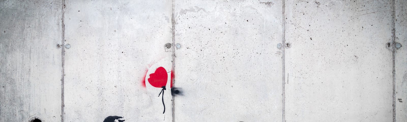 A bright red heart-shaped balloon with a monochromatic girl reaching out to it. Painted on a cement wall.