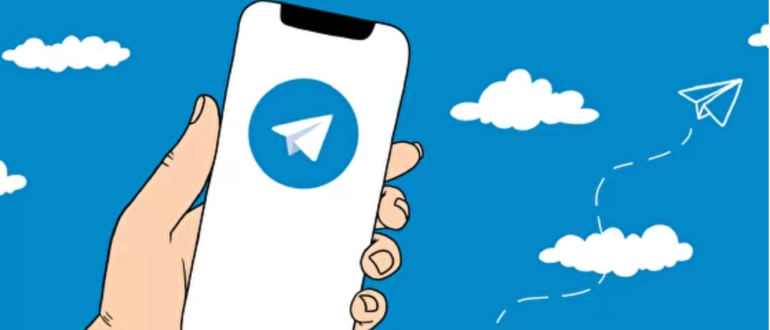 Hand holding a phone. Telegram app logo on the phone.