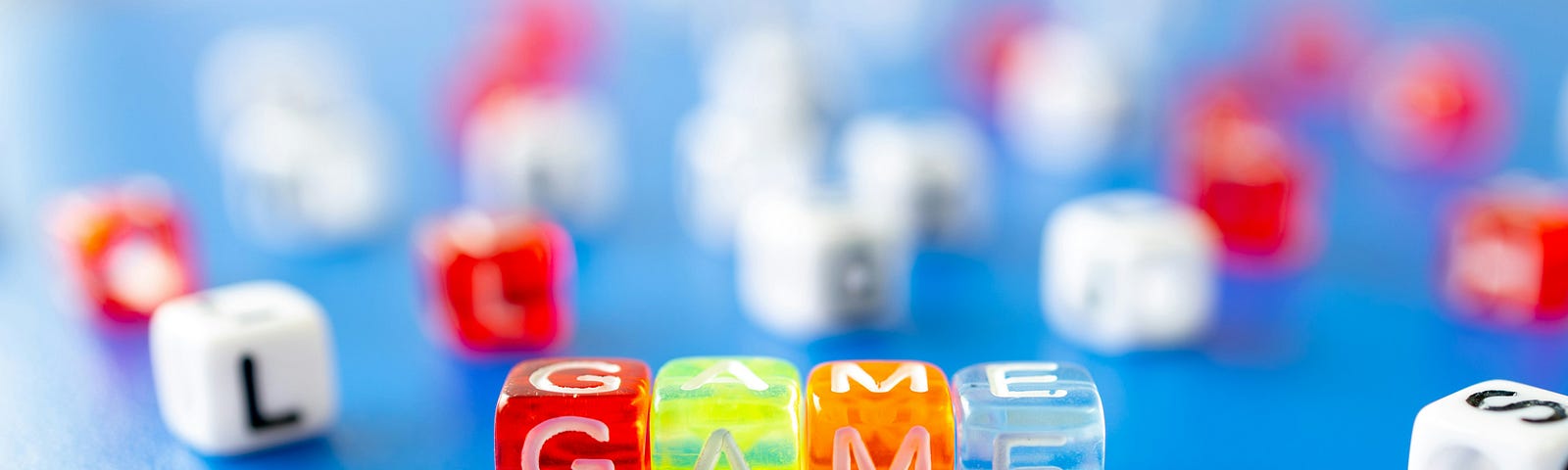 Colorful dice with the letters that spell “game” engraved on them