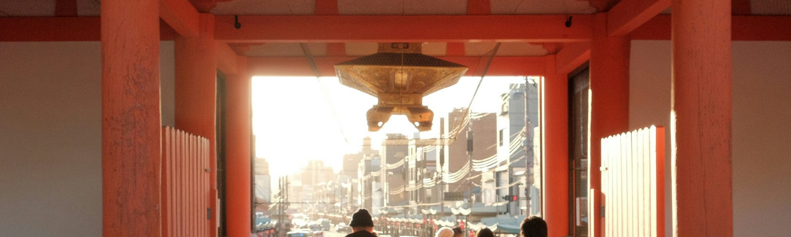 students standing in an orange wooden archway looking out toward a city