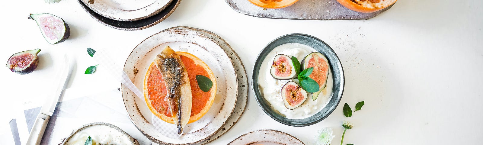 Carious dishes with fruits cut in half on top of them scattered about a table.