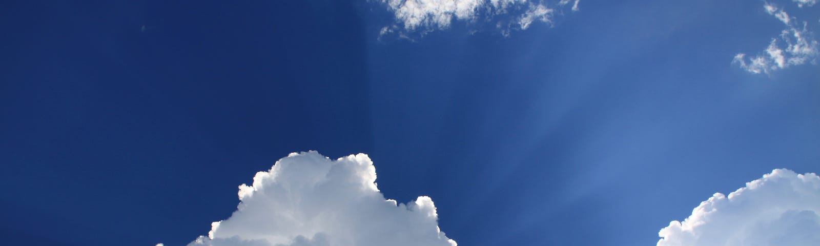 Cumulus clouds in close foreground, with dark blue sky in background.