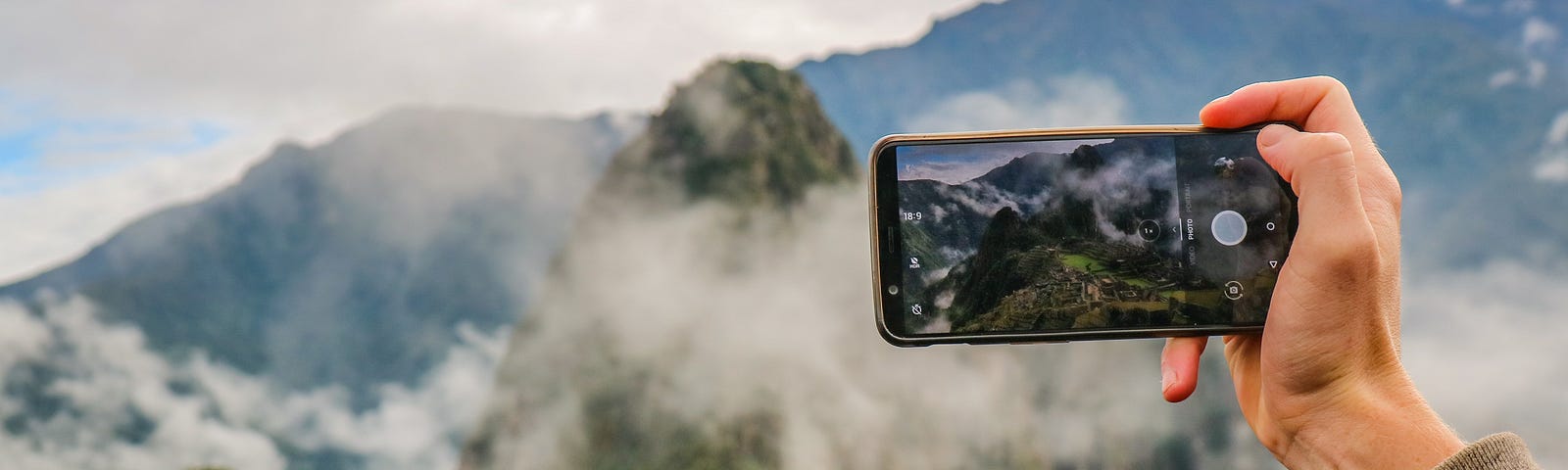 a traveler takes a photo of Machu Pichu