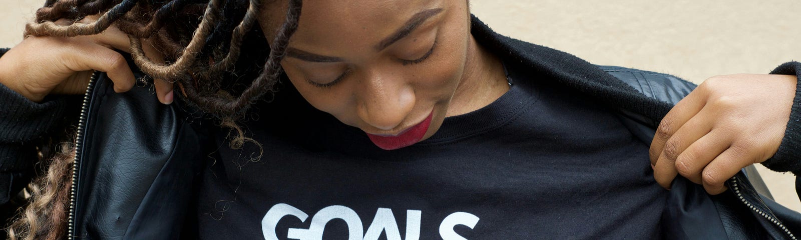 A woman wearing a shirt with words that read “Goals, dreams and melanin.”