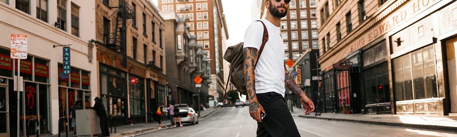 A picture of a man walking on the crosswalk to cross the street.