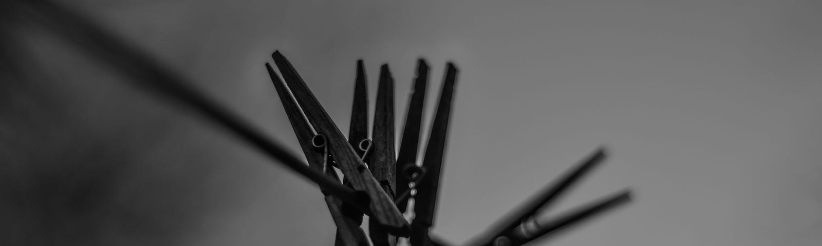 Black and white photo of clothe line with 4 clothes pins on them.