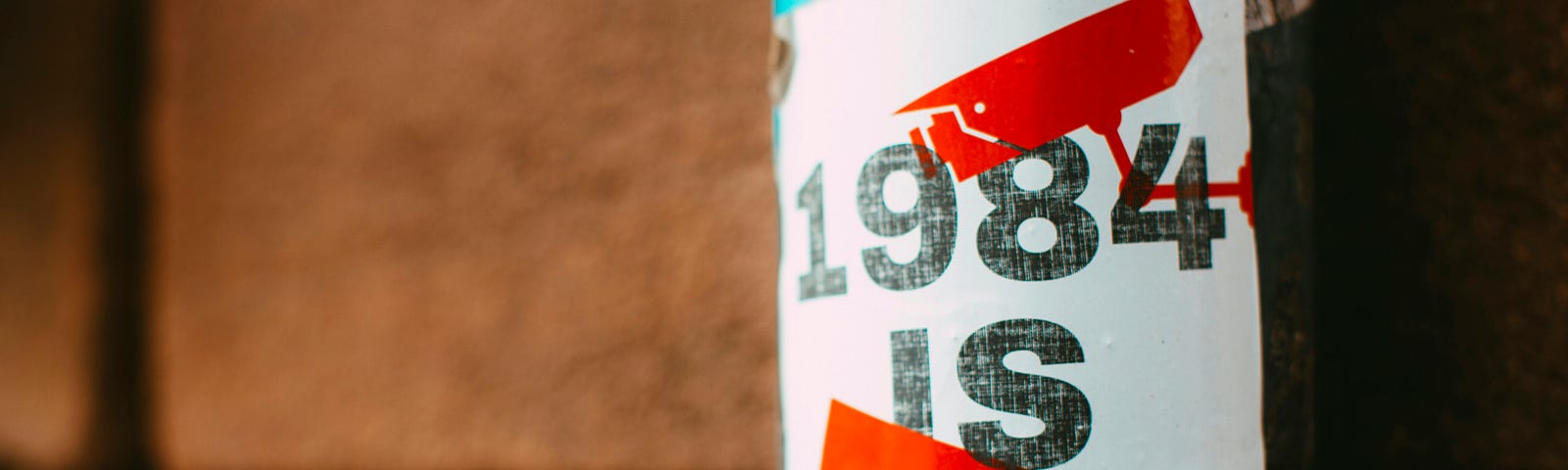 a poster taped on a pole that reads “1984 is now”