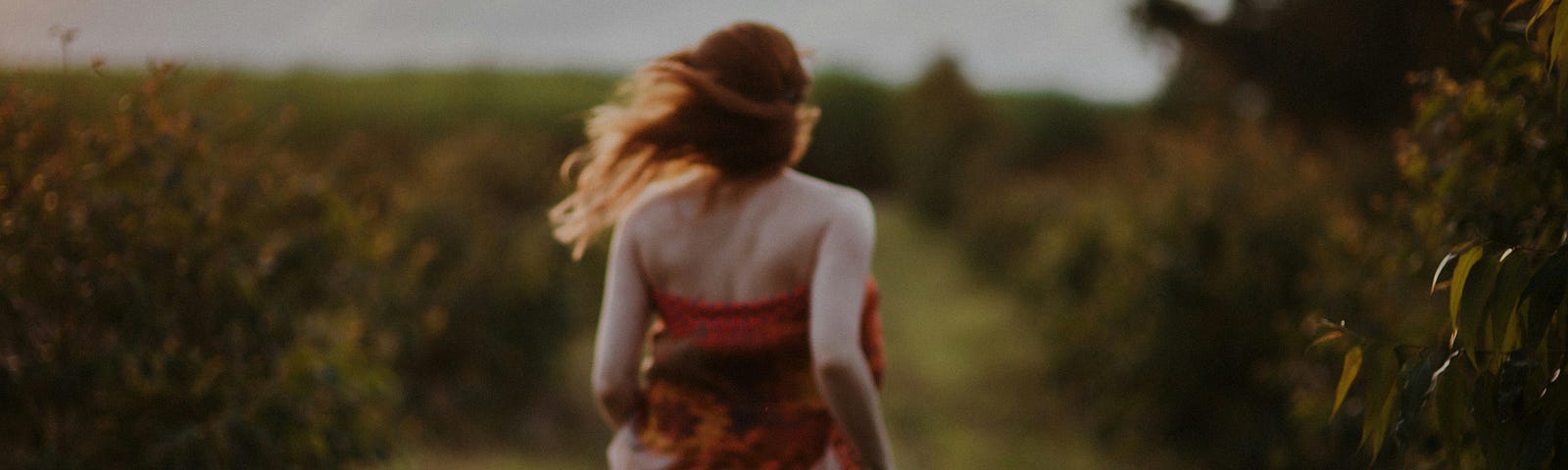 Woman wearing a flowery dress running in a meadow