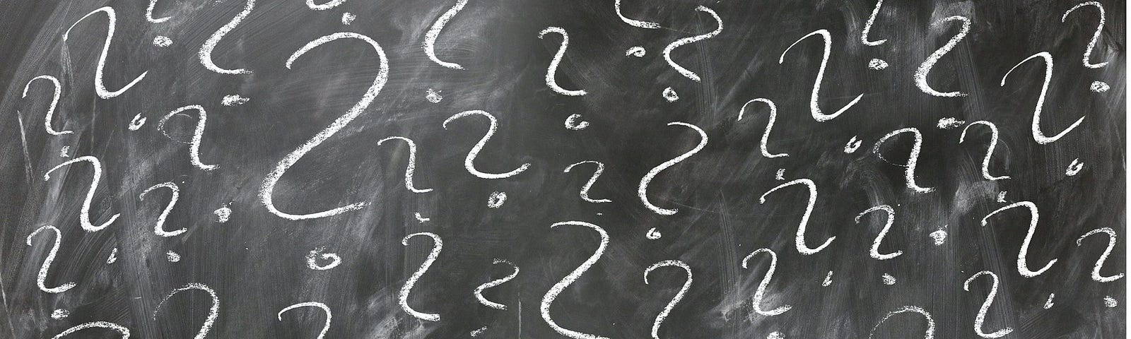 white question marks written on a black chalkboard
