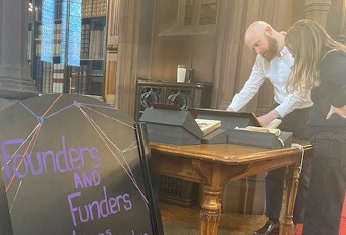 a man and a woman examining books and historical artefacts on a table